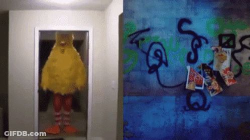 Big Bird Mascot Standing In Doorway Next To Graffiti Wall GIF
