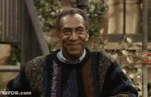 Bill Cosby Is Wearing A Sweater And Smiling While Sitting On A Bench . GIF