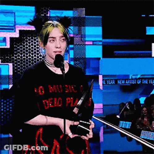 Billie Eilish Is Holding A Trophy And Speaking Into A Microphone At A Awards Show . GIF