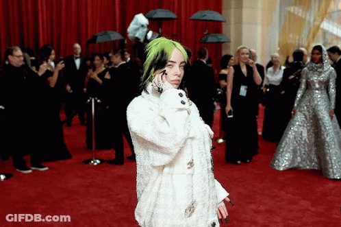 Billie Eilish Is Standing On The Red Carpet Talking On Her Phone GIF
