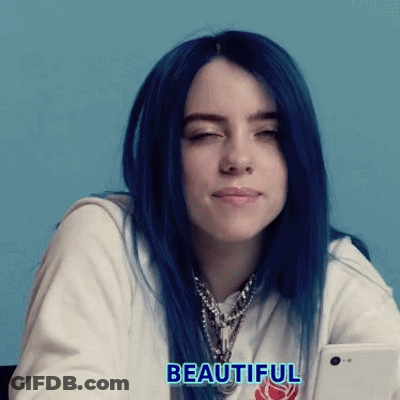 Billie Eilish With Blue Hair Is Holding A Cell Phone In Her Hand . GIF