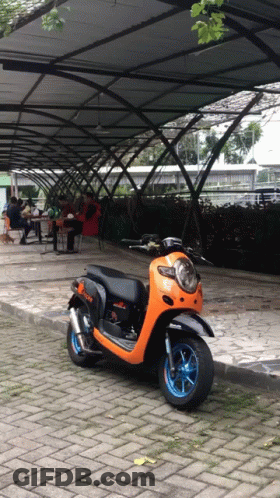 Black And Orange Scooter Parked Under Covered Walkway GIF