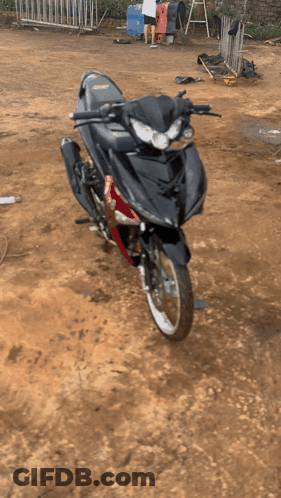 Black And Red Motorcycle Parked On Dirt Field GIF