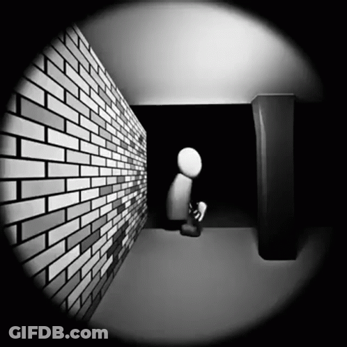 Black And White Brick Wall With Person Kneeling In Dark GIF
