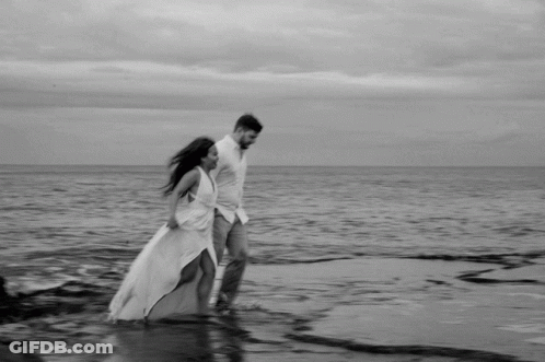 Black And White Couple Walking On Beach GIF