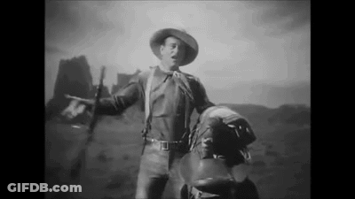 Black And White Cowboy Holding Saddle And Gun GIF