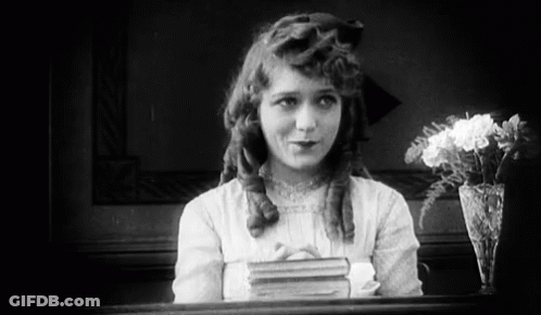 Black And White Girl With Book And Vase Of Flowers GIF