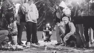Black And White Group Standing Around Wheelchair GIF