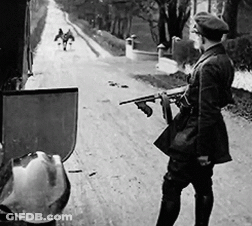 Black And White Man Holding Gun On Dirt Road GIF