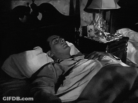 Black And White Man Laying In Bed With Lamp GIF