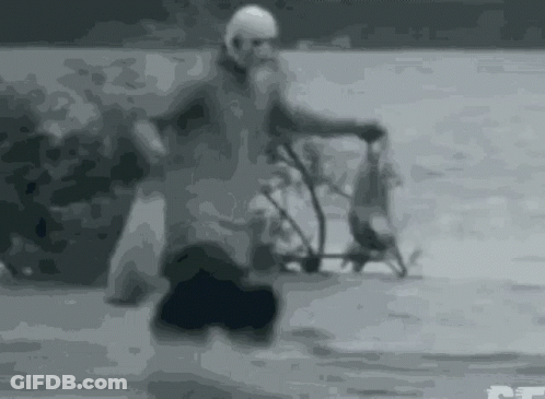 Black And White Man Riding Bike On Snowy Road GIF
