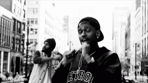 Black And White Man Singing Into Microphone On City Street GIF