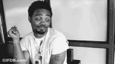 Black And White Man Sitting In Chair With Hands In Pockets GIF