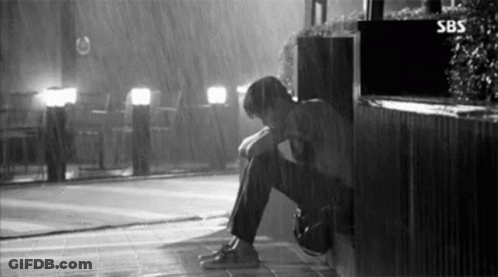 Black And White Man Sitting In Rain Head Down GIF