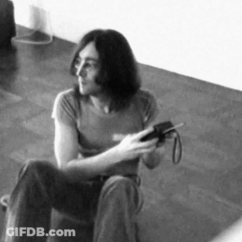 Black And White Man Sitting On Floor Holding Camera GIF