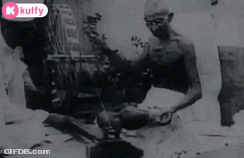 Black And White Man Sitting On Ground With Broom GIF