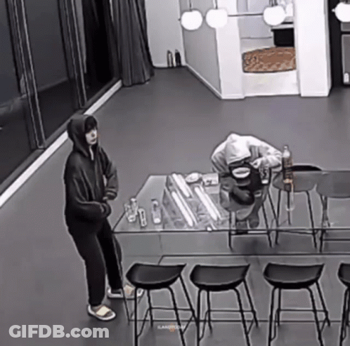 Black And White Man Standing Next To Table With Water Bottle GIF