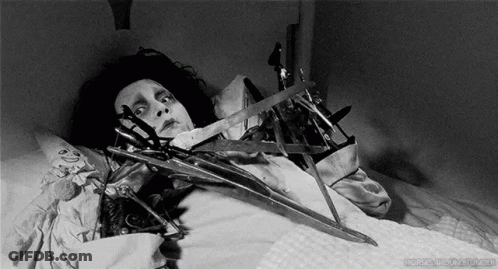 Black And White Person In Bed With Scissors GIF
