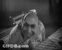 Black And White Photo Of Bald Man Smiling On Bed GIF