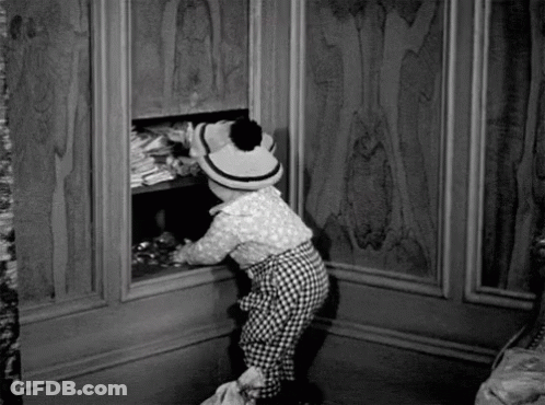 Black And White Photo Of Little Girl In Hat Looking Into Closet GIF