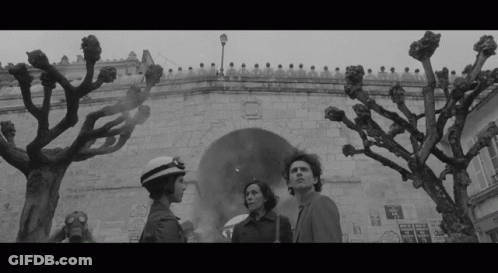 Black And White Photo Of Man And Two Women In Front Of Building GIF