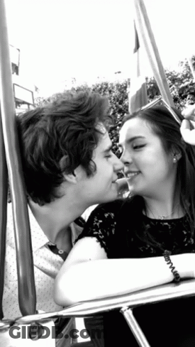 Black And White Photo Of Man And Woman Kissing On Swing GIF