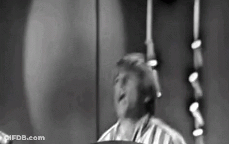 Black And White Photo Of Man Playing Drum Set On Stage GIF