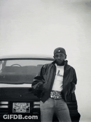 Black And White Photo Of Man Standing In Front Of Car With License Plate Saying X GIF