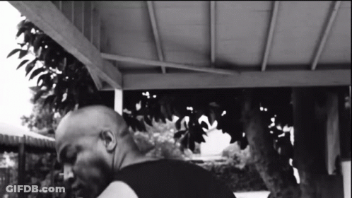 Black And White Photo Of Man Under Porch With Tree GIF