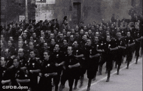 Black And White Photo Of Men Marching Down Street GIF