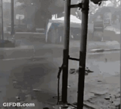 Black And White Photo Of Person Standing Next To Pole In Street GIF