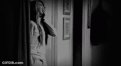 Black And White Photo Of Woman Looking Out Door In Hallway GIF