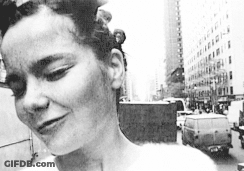 Black And White Photo Of Woman Standing In Front Of Building GIF