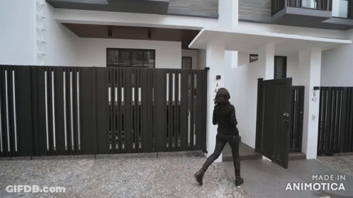 Black And White Photo Of Woman Walking In Front Of Building Made In Animatica GIF