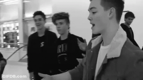 Black And White Photo Of Young Men Standing In Mall GIF