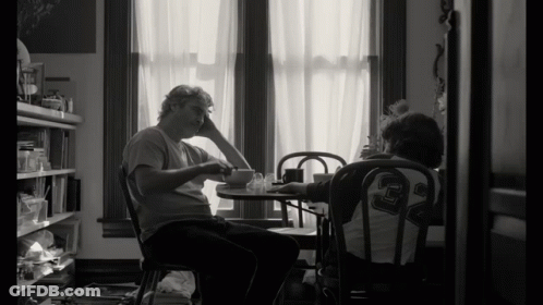 Black And White Photo Two People At Table Man Wearing Number 29 Shirt GIF