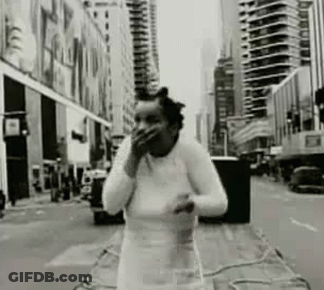 Black And White Woman Covering Mouth On City Street GIF