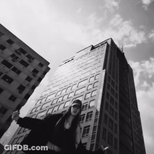 Black And White Woman In Front Of Tall Building GIF