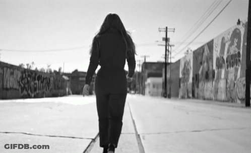 Black And White Woman Walking Past Graffiti Wall GIF