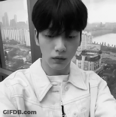 Black And White Young Man In White Jacket Looking Out Window GIF