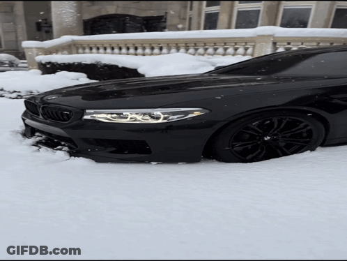 Black BMW Stuck In Snow In Front Of Building GIF