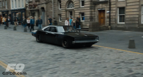 Black Car Driving On Cobblestone Street GIF