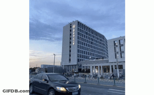 Black Car Driving Past Building With Chinese Writing GIF