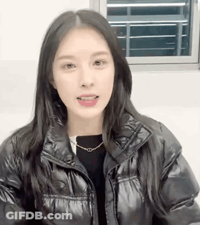 Black Jacket Woman With Necklace Looking At Camera GIF