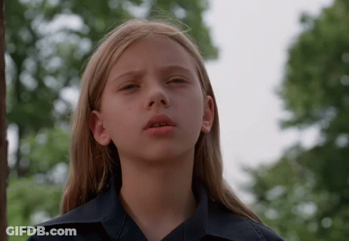 Blonde Girl In Blue Shirt Looking At Camera GIF