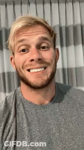 Blonde Haired Man With Beard Smiling In Front Of Curtain GIF