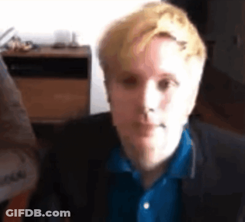 Blonde Man In Blue Shirt And Black Jacket Looking At Camera GIF