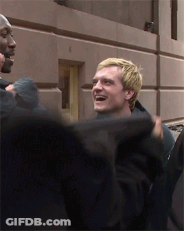 Blonde Man Smiling In Front Of Building Number 8 GIF