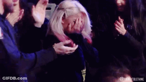 Blonde Woman Covering Face As Crowd Applauds GIF