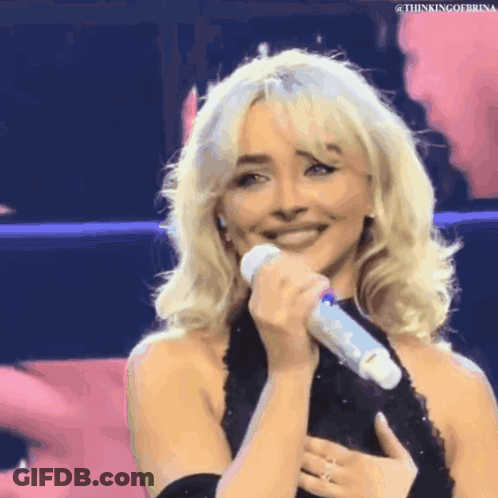 Blonde Woman In Black Dress Holding Microphone Smiling GIF